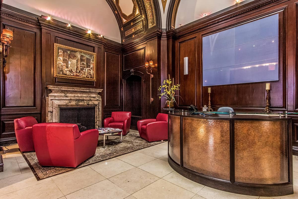 Lobby of the 250 S. 17th St luxury building in Philadelphia featuring large curved wood desk and 4 red arm chairs